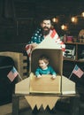 American cheerful family with usa flags play with rocket made out of cardboard box. Child cute boy play cosmonaut