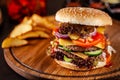 American cuisine concept. A large homemade burger with a double pork and veal meat patty, tomato, cucumber, lettuce, and cheese. Royalty Free Stock Photo