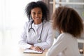 Friendly black therapist listening adolescent girl during reception