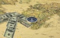 American dollars in form of arrow that indicates direction and navigation compass on old vintage world map as symbol of tourism wi