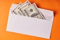 American dollars in a white envelope. Orange background