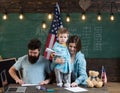 American family at desk with son making paper planes. Kid with parents in classroom with usa flag, chalkboard on Royalty Free Stock Photo