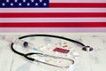American flag on the background of pills and a stethoscope on the table. USA flag and medical supplies