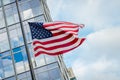 American flag blowing in the wind with building in the back