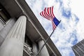 American Flag Blowing in the Wind in Front of Stone Column Build with sky and clouds in background Royalty Free Stock Photo