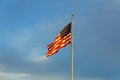 American flag on flagpole waving in the wind against clouds, blue sky Royalty Free Stock Photo