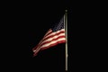 American flag flapping and flying high in night darkened sky