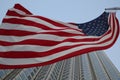American flag fluttering in the wind against a skyscraper