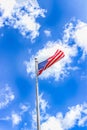 American flag flutters in the wind against the blue sky with white clouds Royalty Free Stock Photo