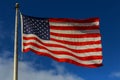 American flag flying the breeze against a blue sky with white clouds Royalty Free Stock Photo