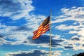 American flag flying in the breeze against blue sky with white clouds Royalty Free Stock Photo