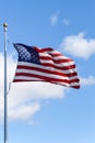 American flag flying in a breeze against a sunny blue sky with light white clouds Royalty Free Stock Photo