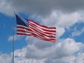 American Flag Flying in front of a Blue Cloudy sky Royalty Free Stock Photo