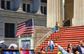 American Flag in front of Federal Hall with people sitting on red stairs on the front, wall street, Manhattan, New York City Royalty Free Stock Photo