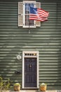 An American flag hung above the door of a colonial style home painted green Royalty Free Stock Photo