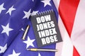 On the American flag lies a pen and a notebook with the inscription - Dow Jones index rose