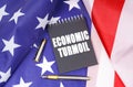 On the American flag lies a pen and a notebook with the inscription - economic turmoil Royalty Free Stock Photo