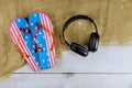 American flag beach slippers sand beach headphones on old wooden background Royalty Free Stock Photo