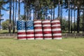 An American flag painted on a stack of large round hay bales in a farm field against a backdrop of pine trees and blue sky Royalty Free Stock Photo