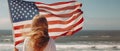 American flag. patriotic girl with long red hair, holding an american flag waving in the wind on the ocean beach. National 4 july