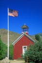 American flag waving above one room schoolhouse,