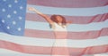 American flag waving against african american woman jumping on the beach Royalty Free Stock Photo