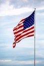 American flag waving on a flagpole in front of clouds Royalty Free Stock Photo