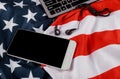 American flag waving with modern smartphone with blank screen, black headphones Royalty Free Stock Photo