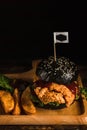 American food background of deep fried chicken black hamburger with BBQ barbeque sauce on wooden plate in dark tone, slective Royalty Free Stock Photo