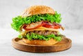 American food concept. Burger with beef and bacon on wooden plate on gray background.