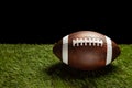 American football ball on green grass field background. Royalty Free Stock Photo