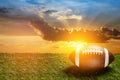 American football ball on green grass field on background of sunset sky. Banner. Royalty Free Stock Photo