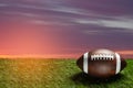 American football ball on green grass field on background of sunset sky. Banner. Royalty Free Stock Photo