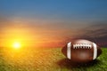 American football ball on green grass field on background of sunset sky. Banner. Royalty Free Stock Photo