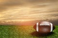 American football ball on green grass field on background of sunset sky. Banner. Royalty Free Stock Photo