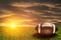 American football ball on green grass field on background of sunset sky. Banner. Royalty Free Stock Photo