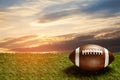 American football ball on green grass field on background of sunset sky. Banner. Royalty Free Stock Photo