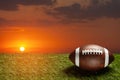 American football ball on green grass field on background of sunset sky. Banner. Royalty Free Stock Photo