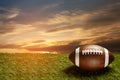 American football ball on green grass field on background of sunset sky. Banner. Royalty Free Stock Photo