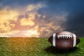 American football ball on green grass field on background of sunset sky. Banner. Royalty Free Stock Photo