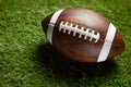 American football ball on green grass field background. Royalty Free Stock Photo