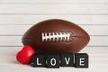 American football ball, heart and cubes with word Love on white wooden table Royalty Free Stock Photo