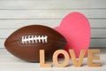 American football ball, heart and word Love on white wooden table Royalty Free Stock Photo