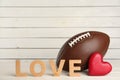 American football ball, heart and word Love on white wooden table. Space for text Royalty Free Stock Photo