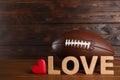 American football ball, heart and word Love on wooden table. Space for text Royalty Free Stock Photo