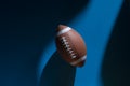 American football ball with natural lighting on blue background. Horizontal sport theme poster, greeting cards, headers, website a Royalty Free Stock Photo