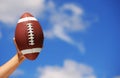 American Football in Hand over Sky Royalty Free Stock Photo