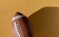 American football leather ball on yellow background