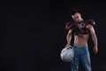 American football player with helmet in hand on black background Royalty Free Stock Photo