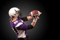 American football player holding ball in his hands in smoke. Black background, copy space. The concept of American